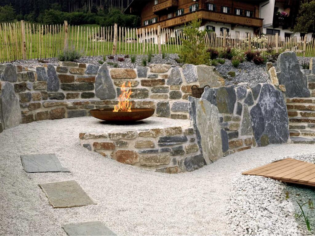 Gartengestaltung mit hochwertigem Naturstein schafft Kraftplatz mit Feuerstelle